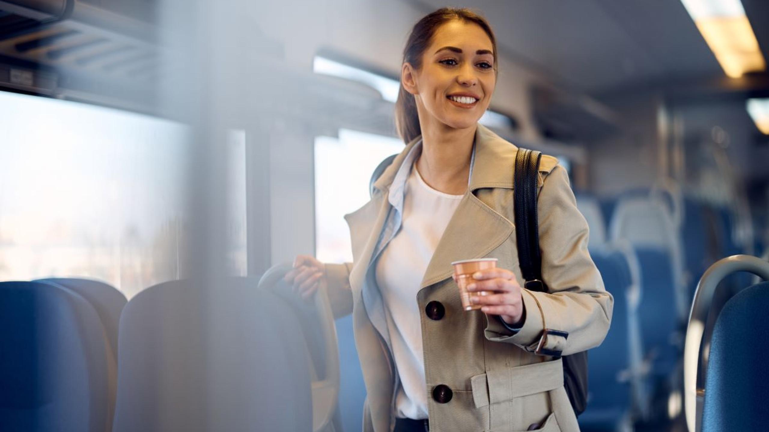 Vrouw in de trein met koffie in de hand.