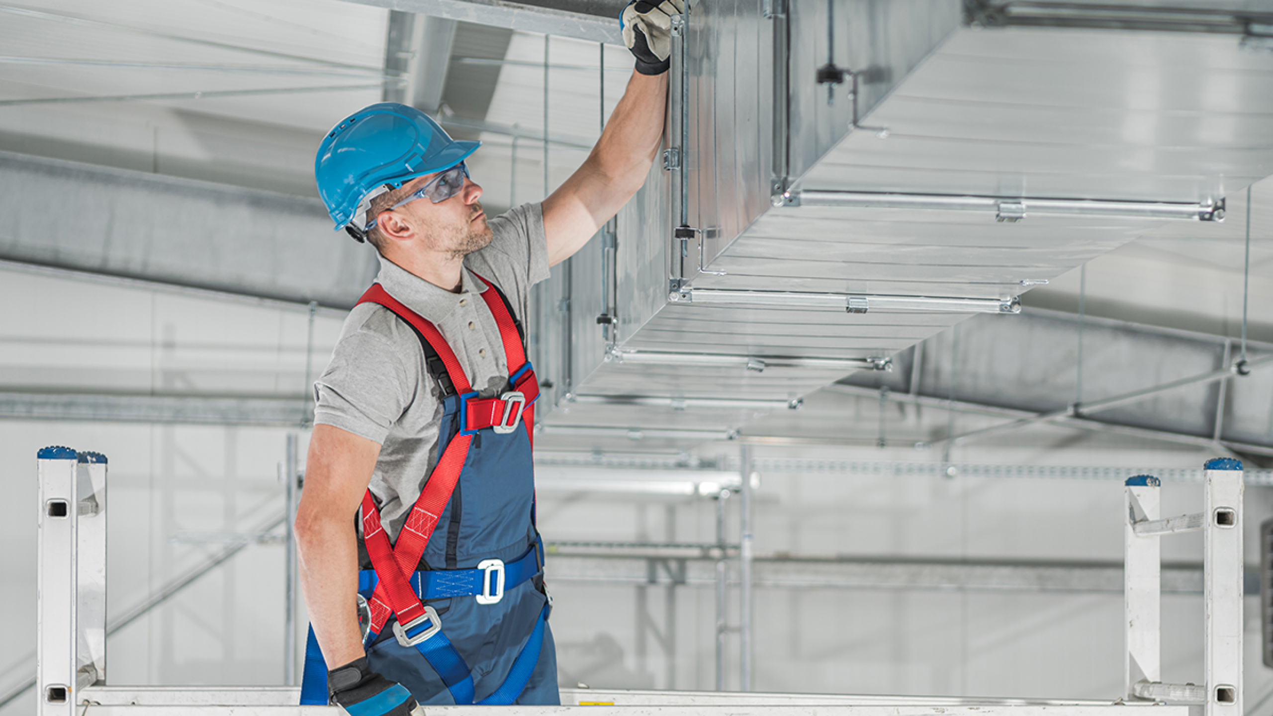 HVAC-technicus op steiger en met valbeveiliging.