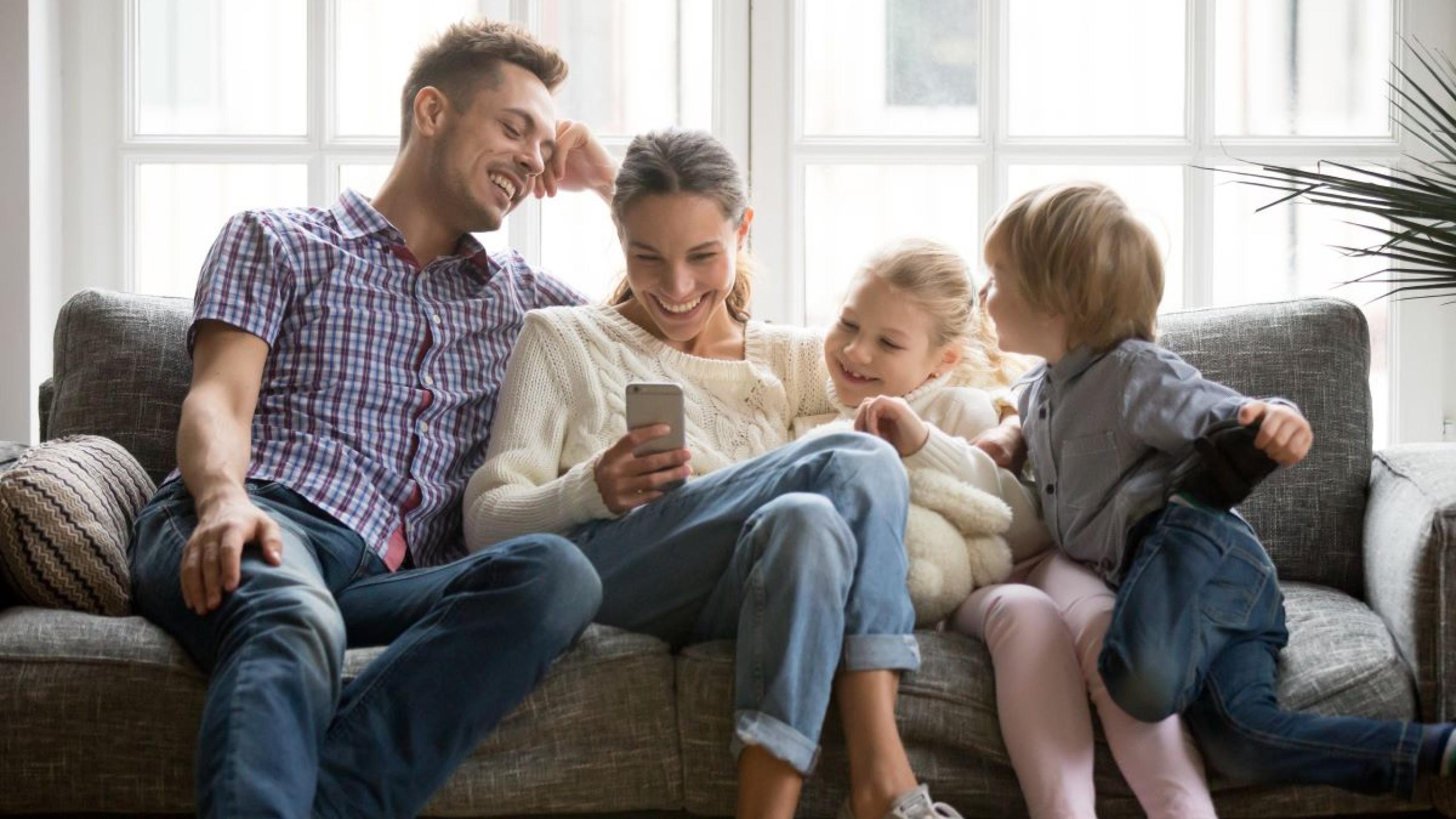 Gezin met man, vrouw en twee kinderen op de sofa.