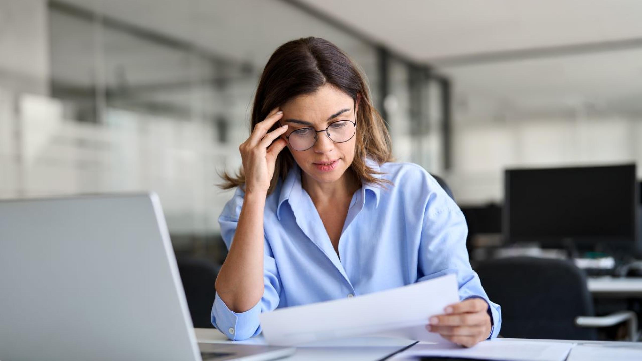 Verontruste zakenvrouw leest brief aan bureau.