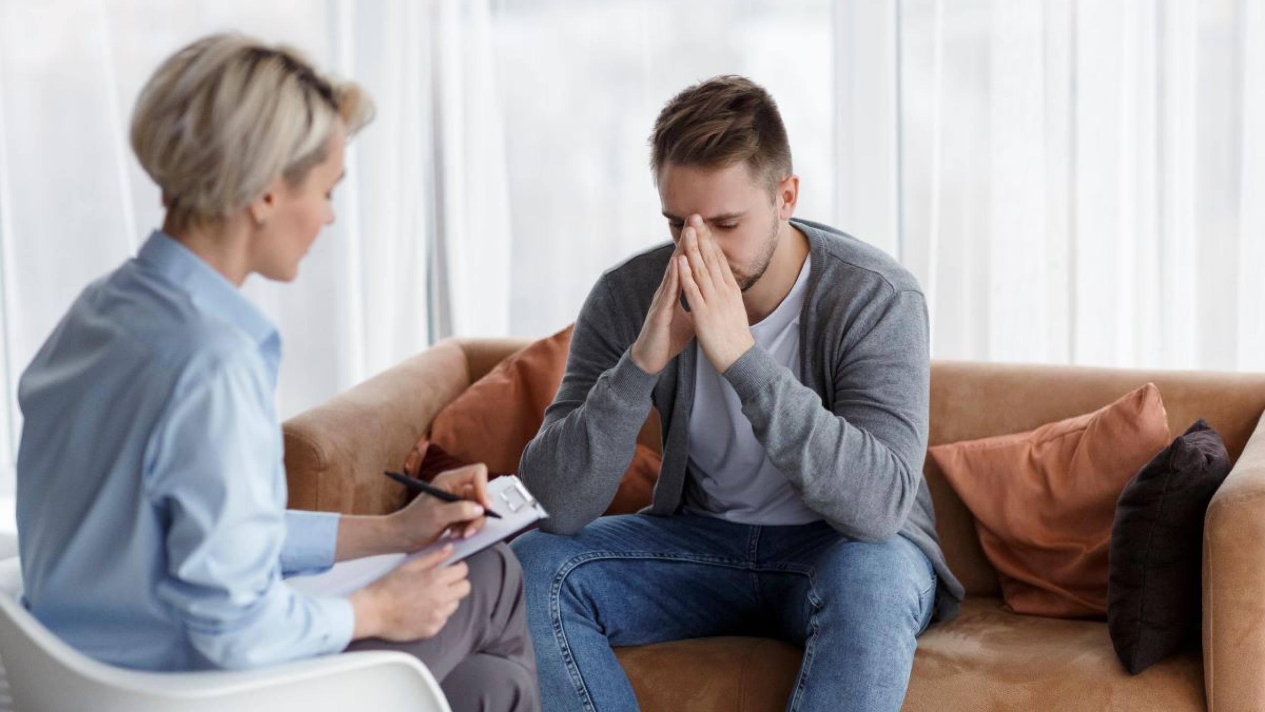 Jonge man op zitbank bij psycholoog.