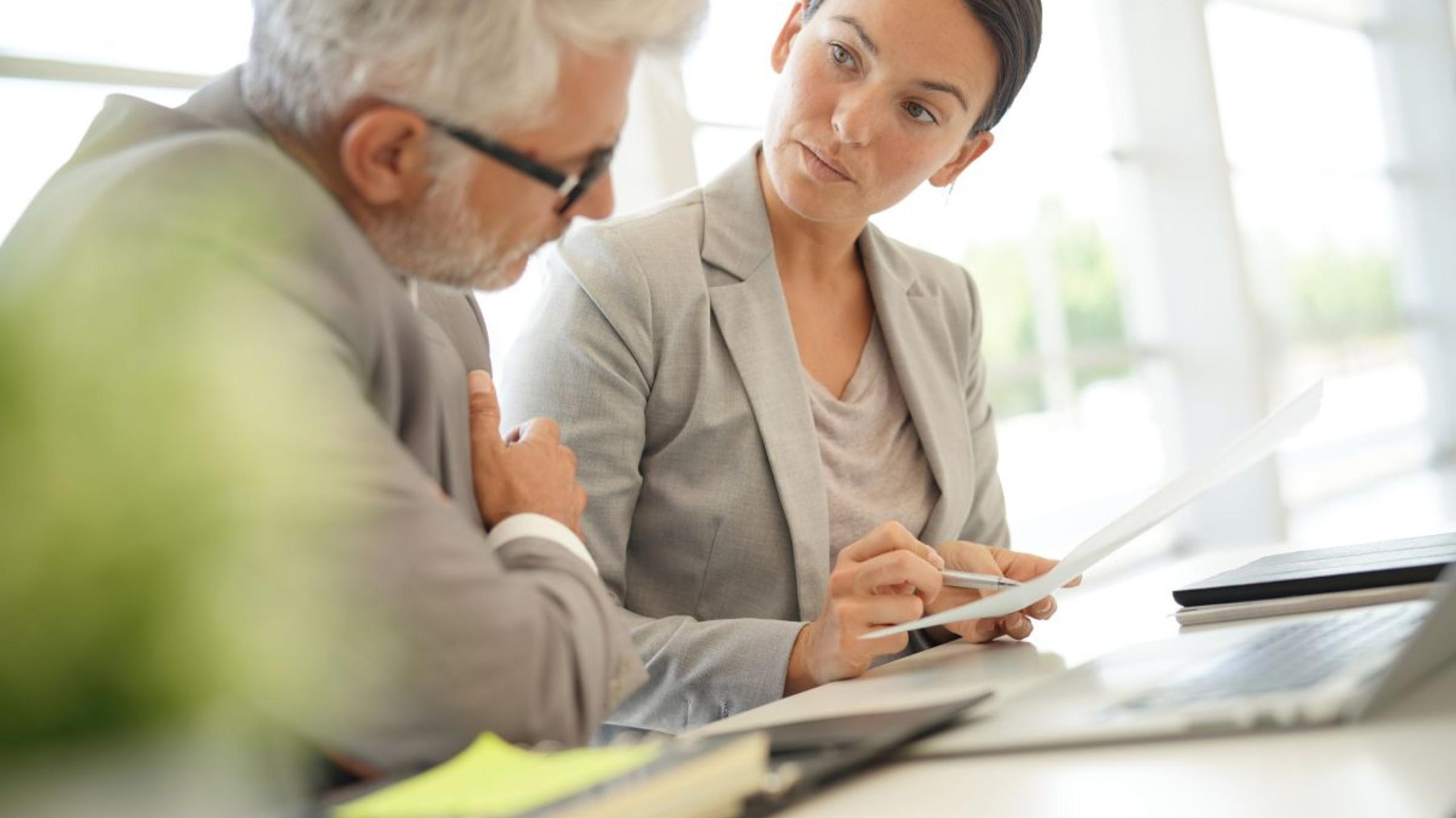 Man luistert op kantoor naar vrouw die uitleg geeft.
