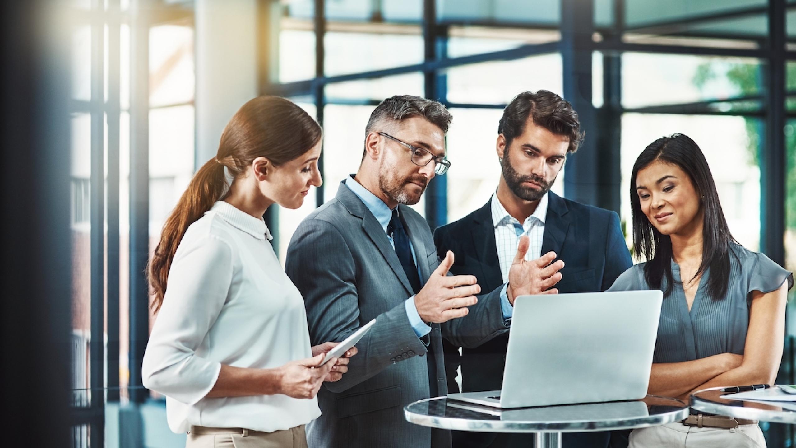 Groep juristen staat rond laptop.